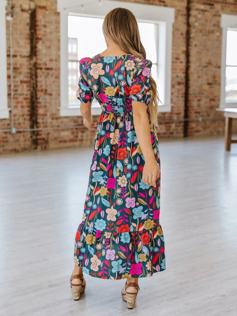 Maxi -dress features elegant puff sleeves, a flowy silhouette, and a bright floral print.