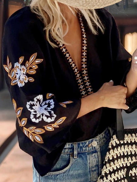 Black v-neck top with stunning embroidered detail on the sleeve.