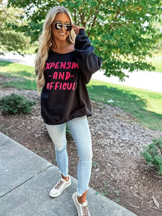 This Black Sweatshirt features a sassy "Expensive And Difficult graphic in playful pink puff font. 