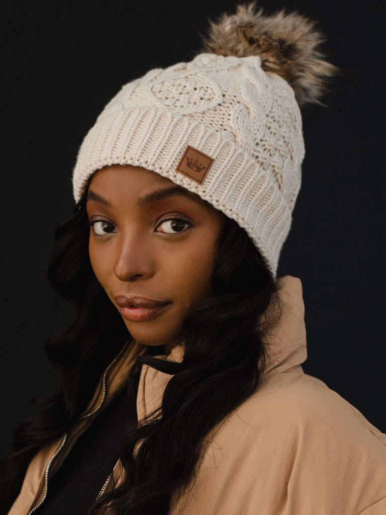Beige cable knit pom hat, 100% acrylic and fleece-lined.