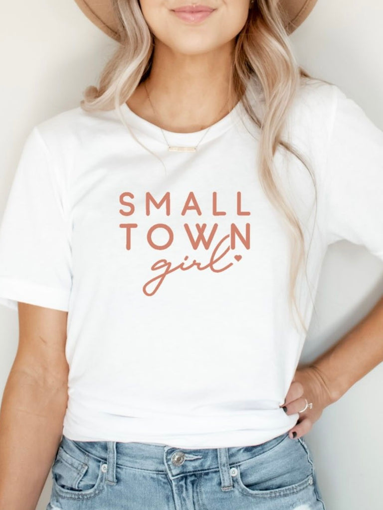 Relaxed Fit White Tee, features a charming blush pink "Small Town Girl" font made from lightweight, super-soft fabric for ultimate comfort.