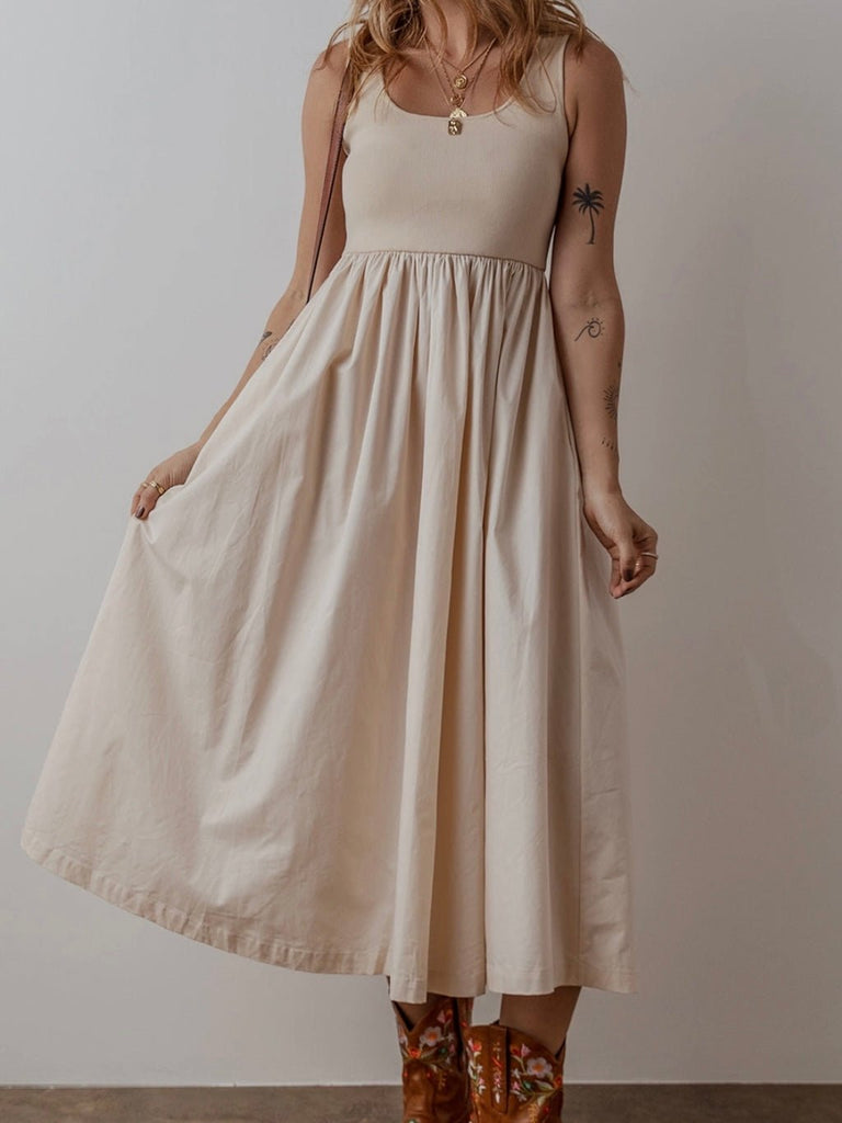 Woman wearing neutral boho sleeveless midi dress with ribbed bodice and pleated skirt