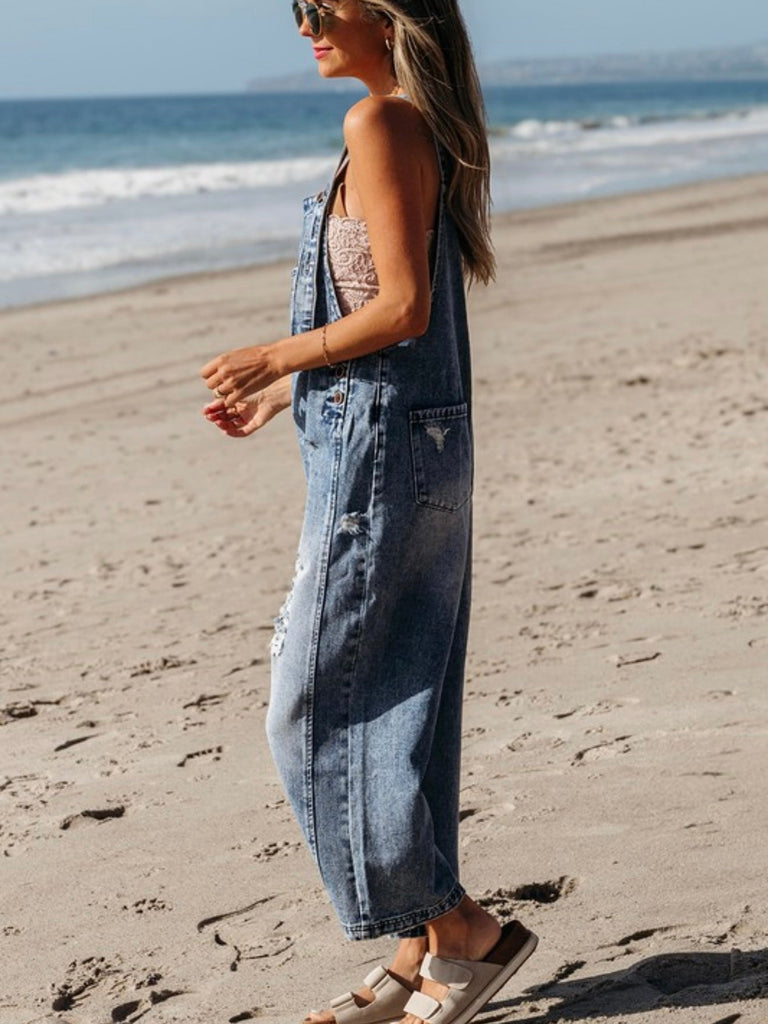 Side profile of woman in casual blue denim overalls, beach background