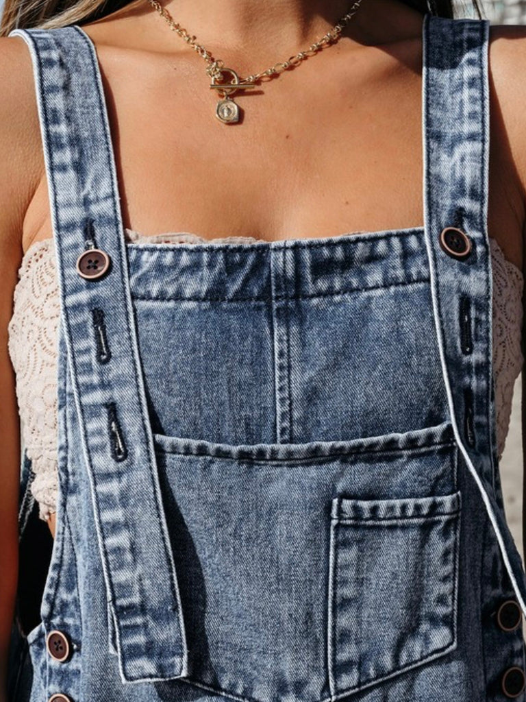 Close-up of distressed denim bib overalls with front pocket detail