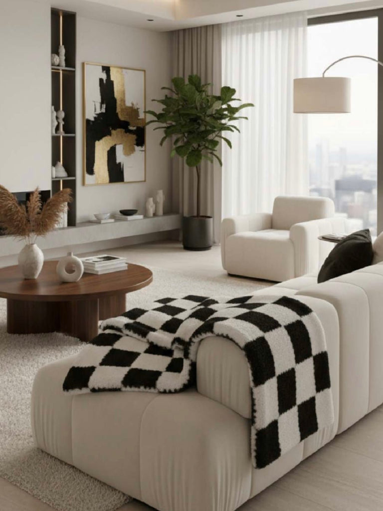 Modern living room with white sofa, checkered blanket, and decorative items.