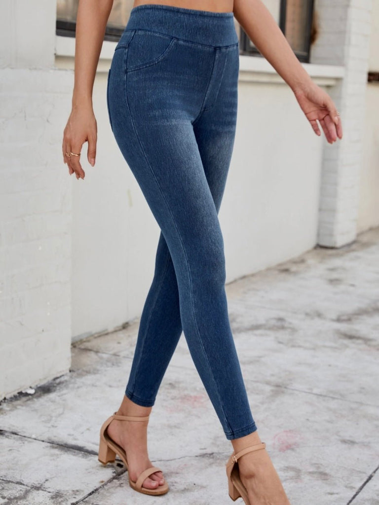 Model walking in blue denim pull-on jeggings styled with a black crop top and heels.