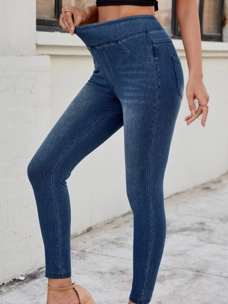 Side view of high-waisted dark blue jeggings with a pull-on waistband, styled with nude heels.