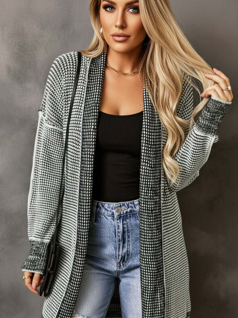 Woman wearing a checkered black and white cardigan over a black top and blue jeans