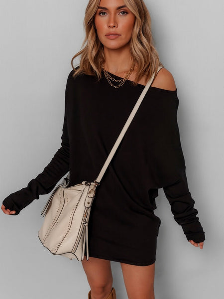 Woman wearing a black off-shoulder dress with a beige handbag