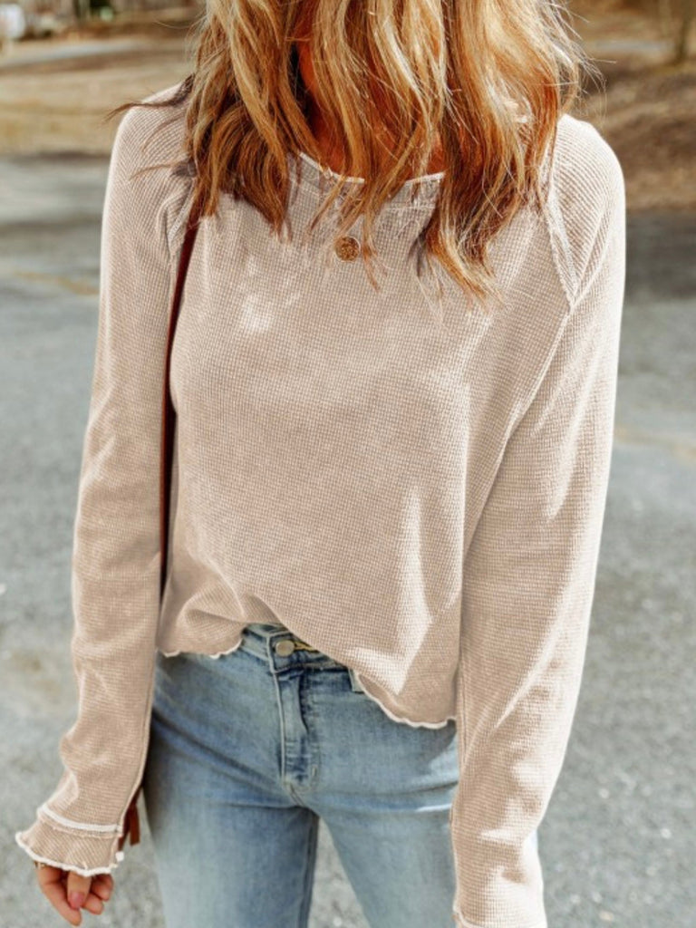 Woman wearing a beige long-sleeve thermal shirt and light blue jeans.