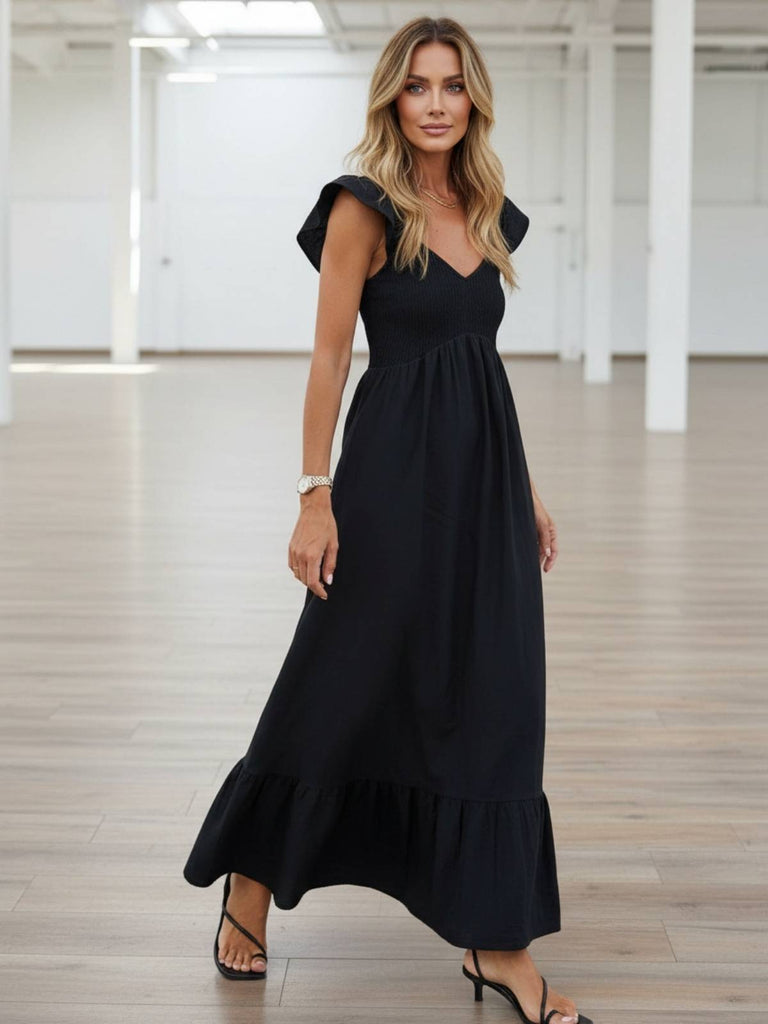 Woman wearing a black maxi dress with ruffle cap sleeve and smocked top