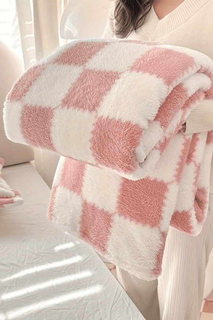 Pink and white checkered blanket held by a person in a home setting
