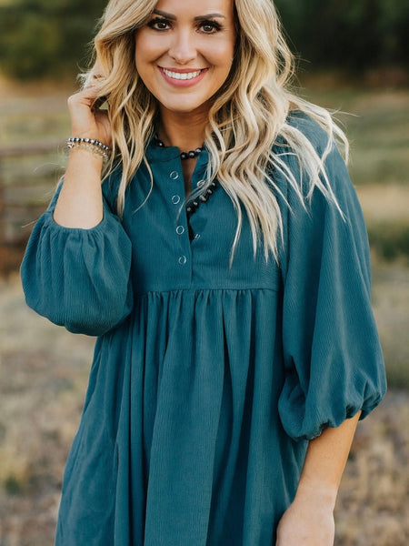 Woman wearing a teal corduroy dress