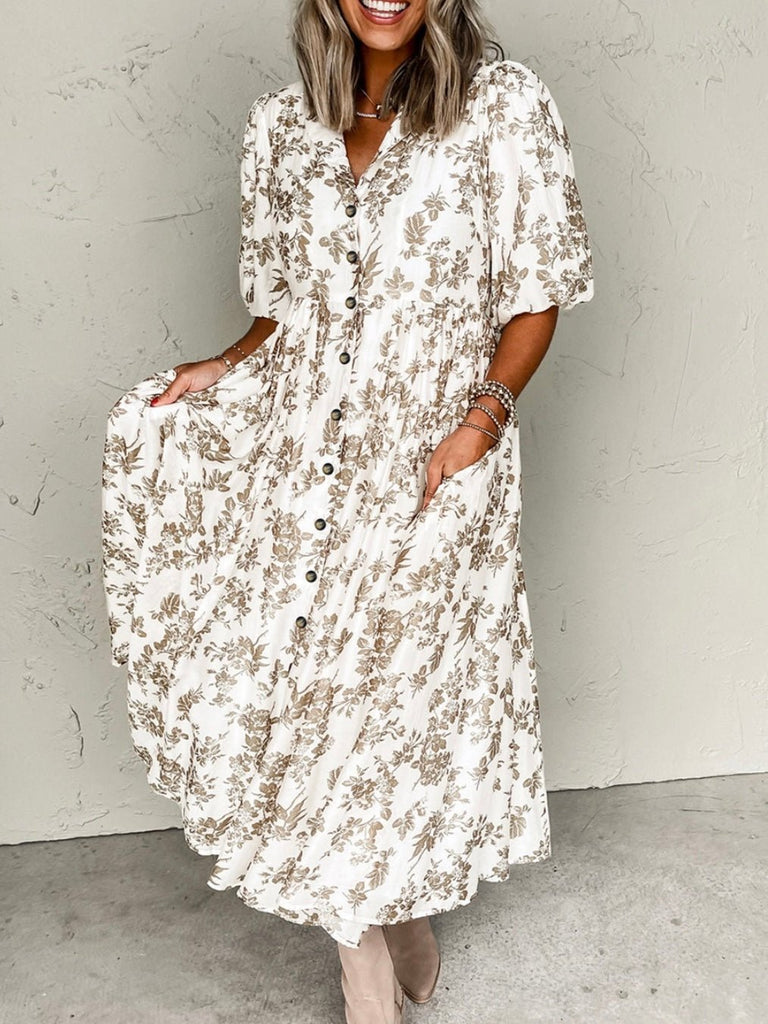 A woman wearing a floral button-up midi dress with a V-neckline, short puff sleeves, and side pockets.