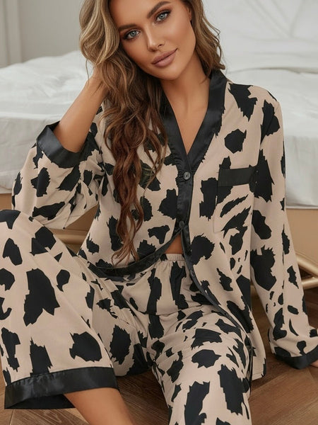 Woman wearing a brown neutral leopard print pajama set with long sleeves sitting on a bed.
