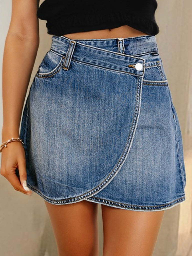Close-up of a high-waisted denim mini skirt with wrap front detail, styled with a black crop top.