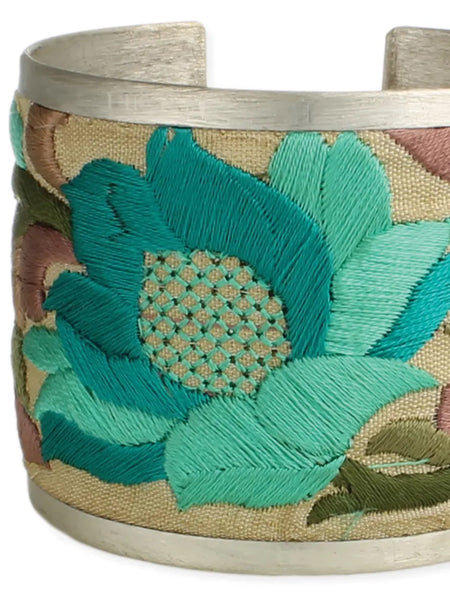  2" Wide Brushed Silver Cuff with bold cream coloured fabric embroidered with turquoise and purple floral designs. 